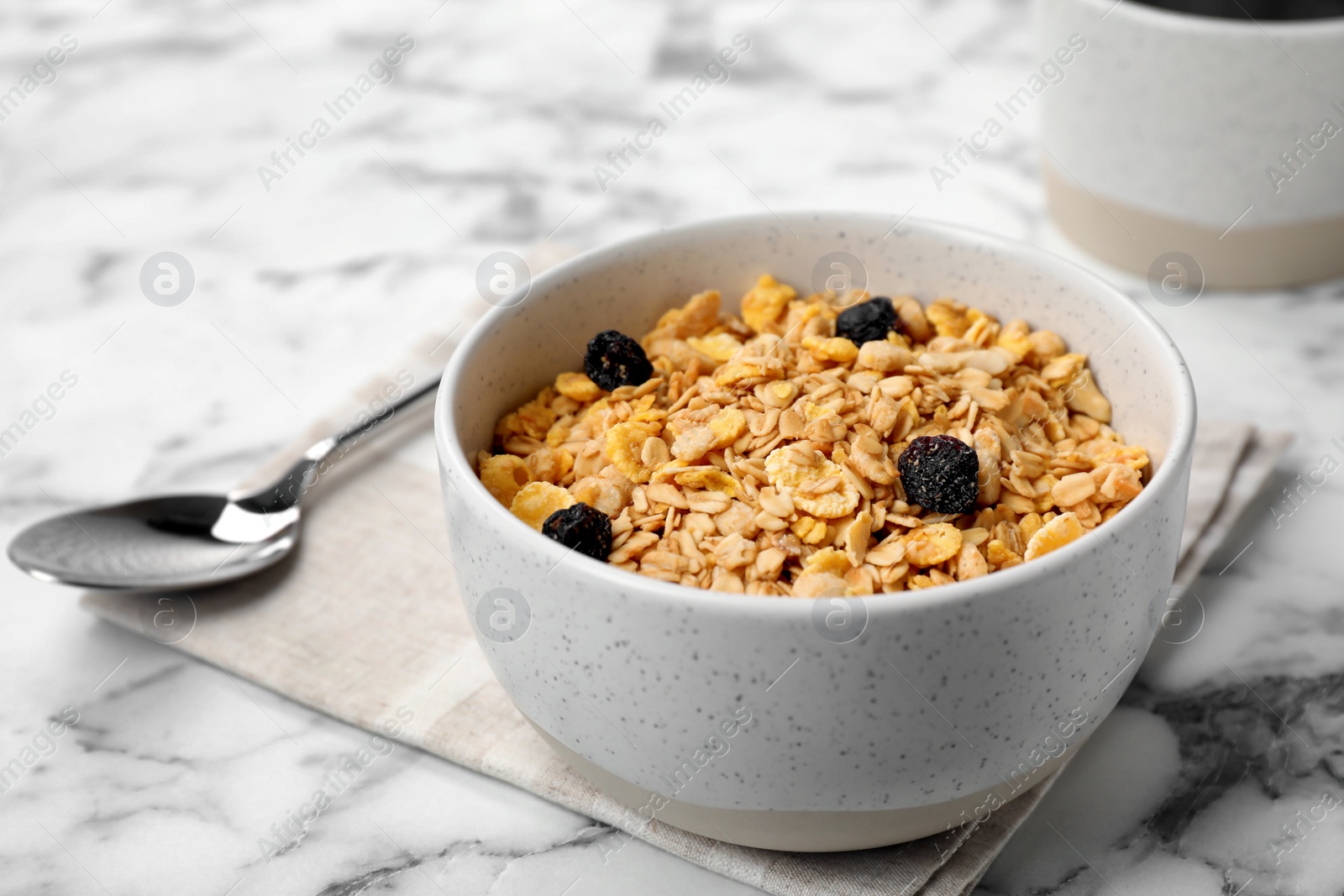 Photo of Bowl with whole grain cereal and raisins on marble table