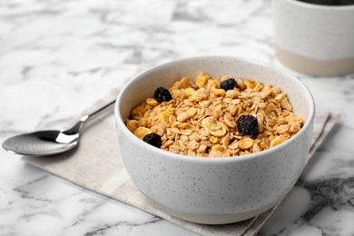 Photo of Bowl with whole grain cereal and raisins on marble table