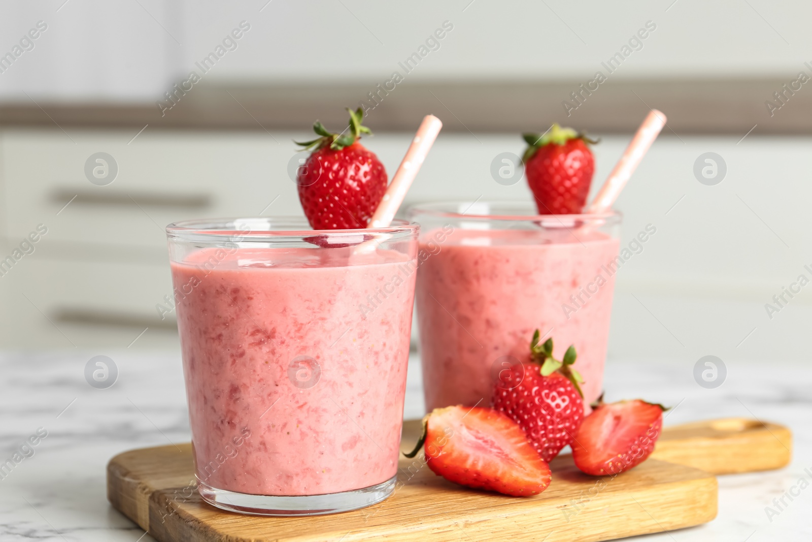 Photo of Tasty strawberry smoothies in glasses on wooden board