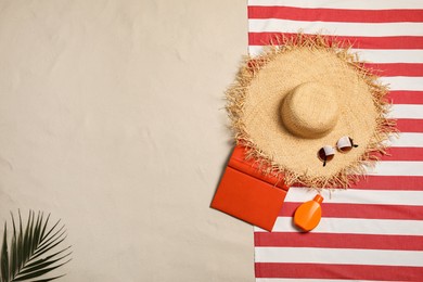 Photo of Beach towel, hat, sunglasses, sunscreen and book on sand, flat lay. Space for text