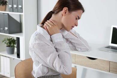 Photo of Woman suffering from neck pain in office