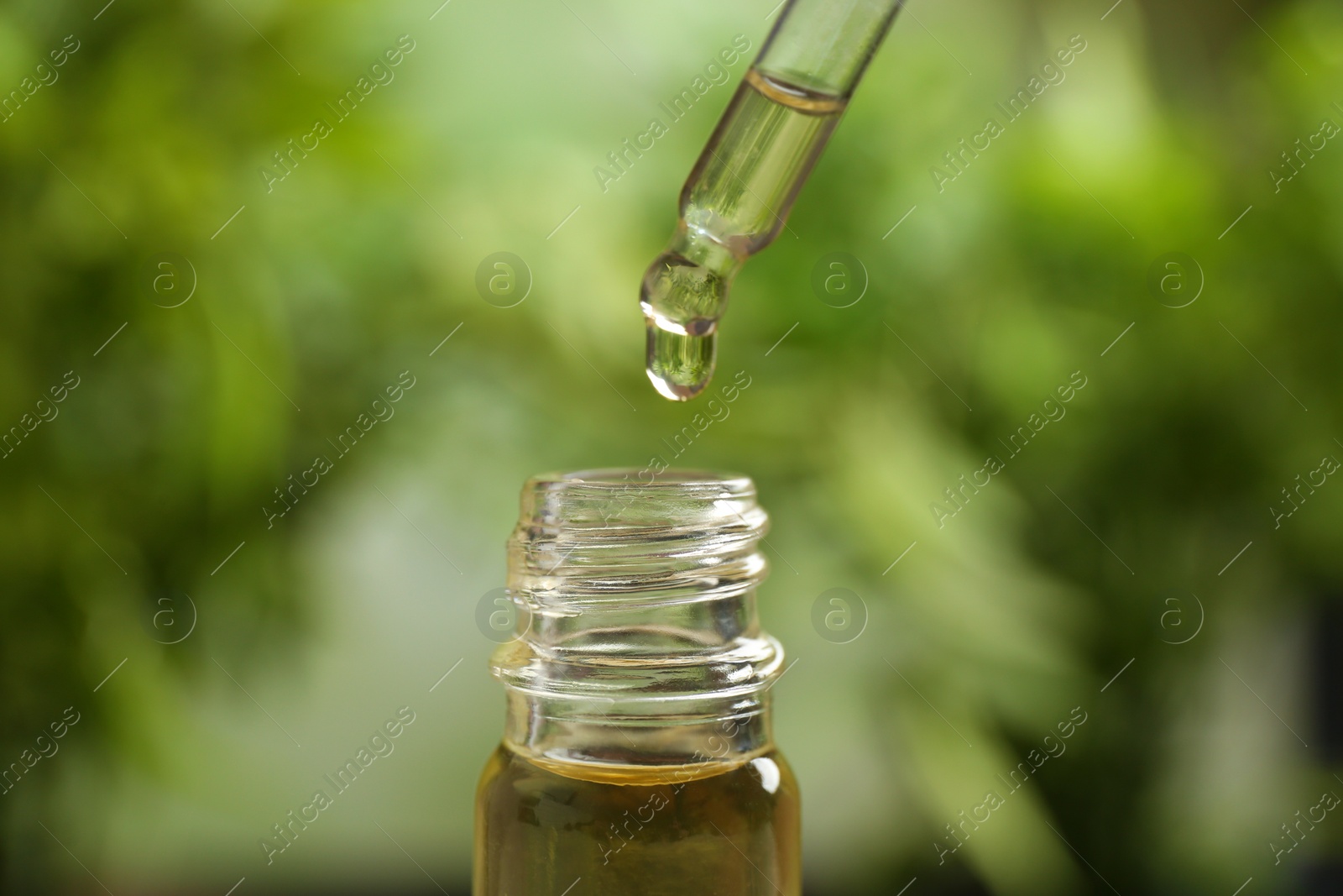 Photo of Pipette and bottle of essential oil on blurred background, closeup