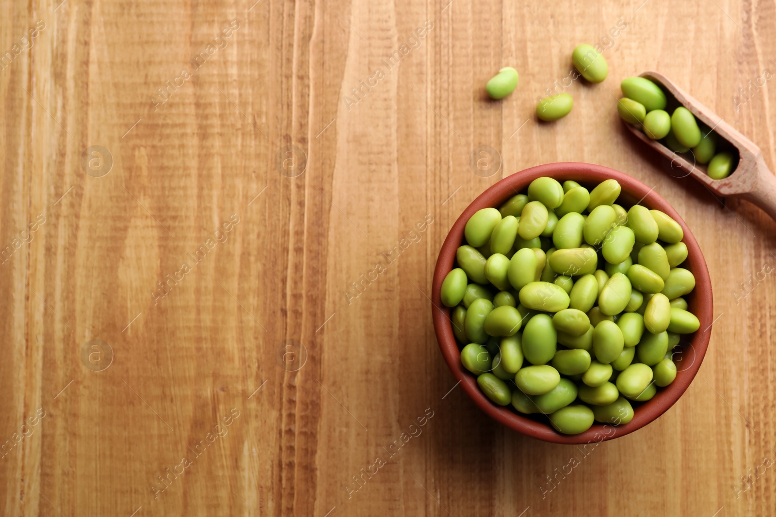 Photo of Organic edamame beans on wooden table, flat lay. Space for text