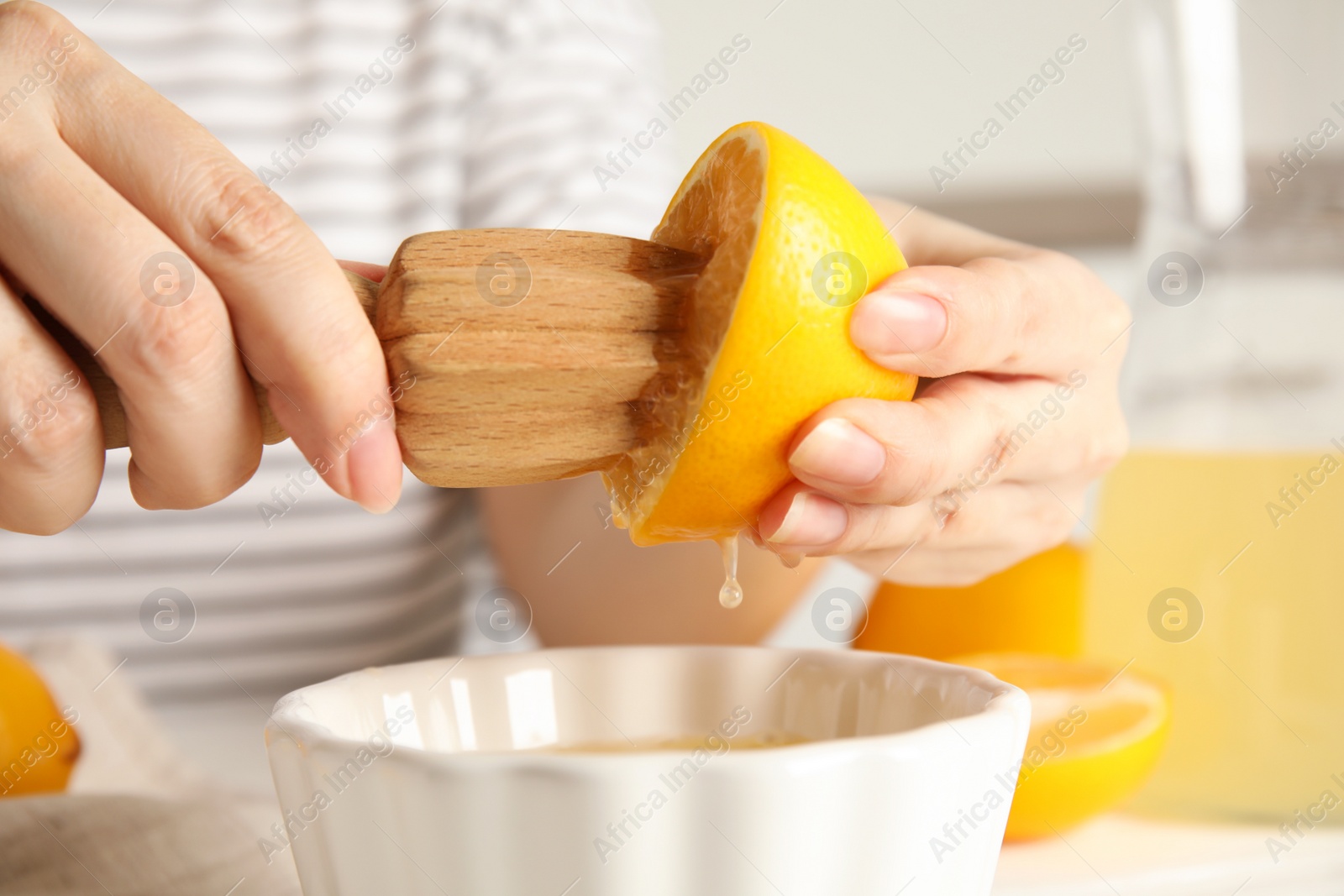 Photo of Woman squeezing lemon juice with wooden reamer, closeup