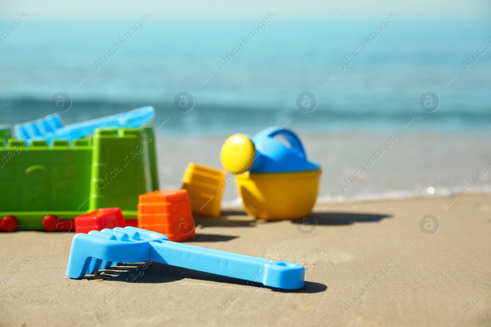 Photo of Different child plastic toys on sandy beach. Space for text