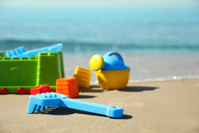 Photo of Different child plastic toys on sandy beach. Space for text