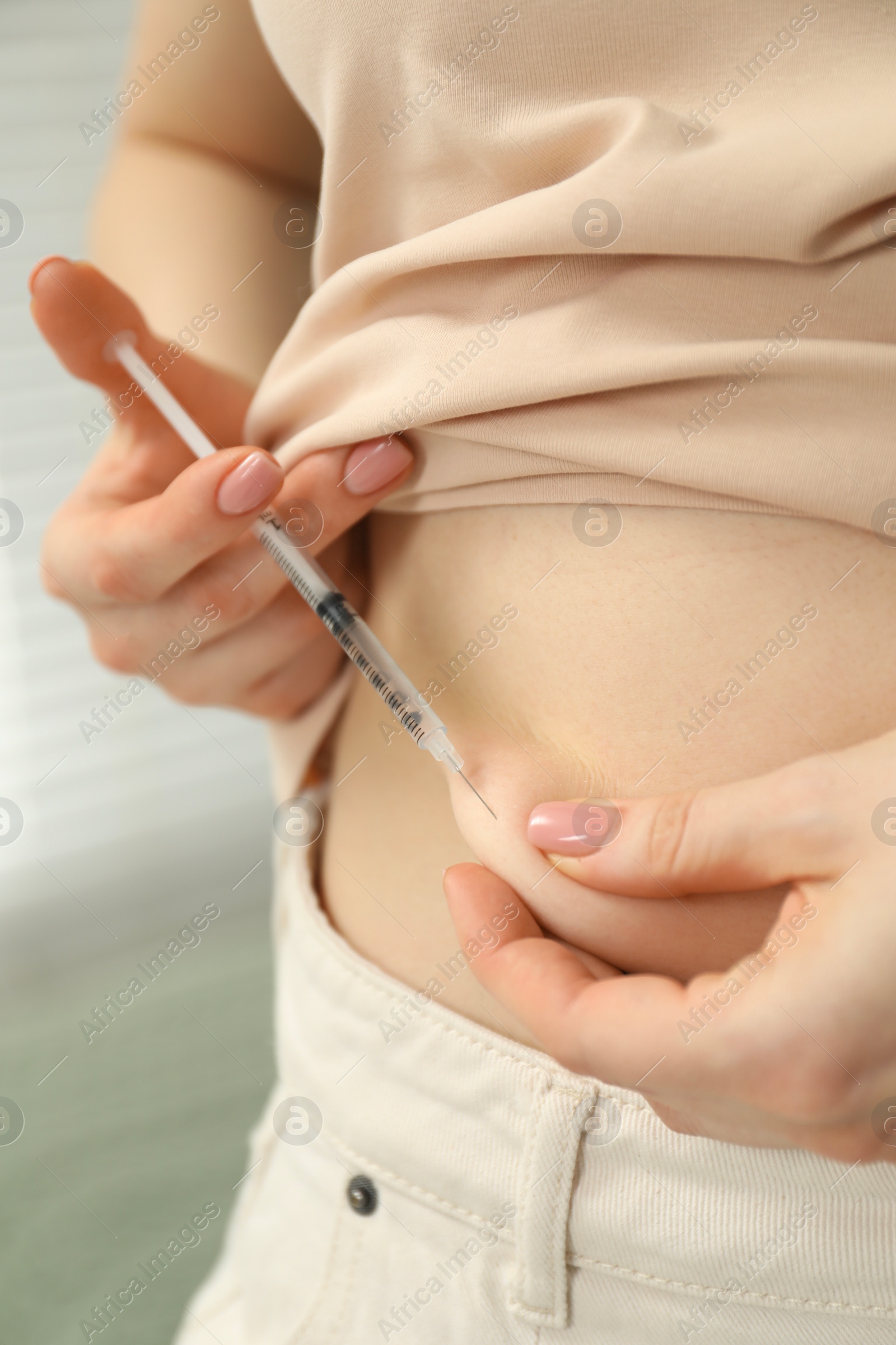 Photo of Diabetes. Woman making insulin injection into her belly indoors, closeup