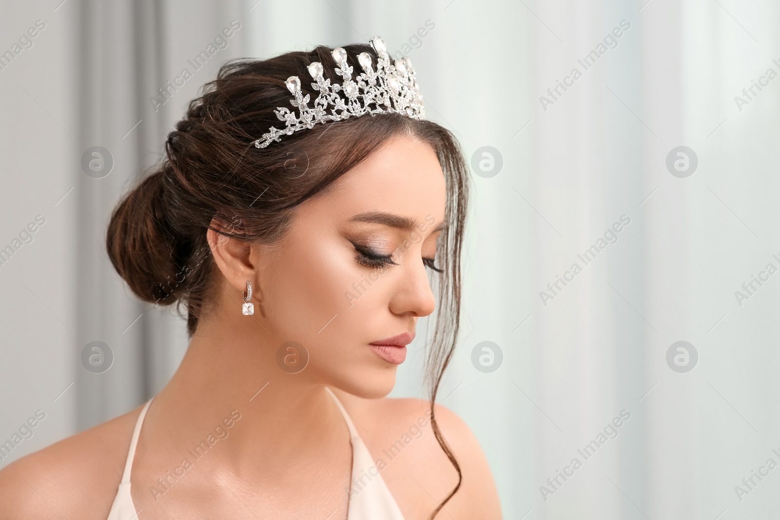 Photo of Beautiful young woman wearing luxurious tiara indoors, space for text