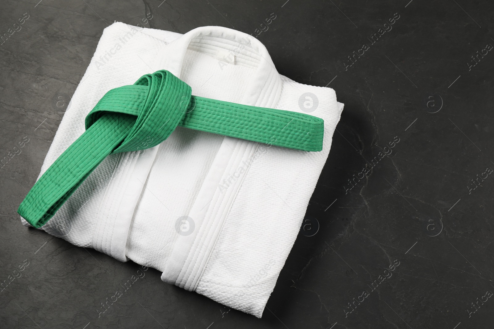 Photo of Green karate belt and white kimono on gray background, top view. Space for text