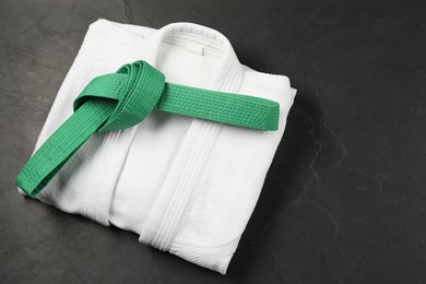 Photo of Green karate belt and white kimono on gray background, top view. Space for text