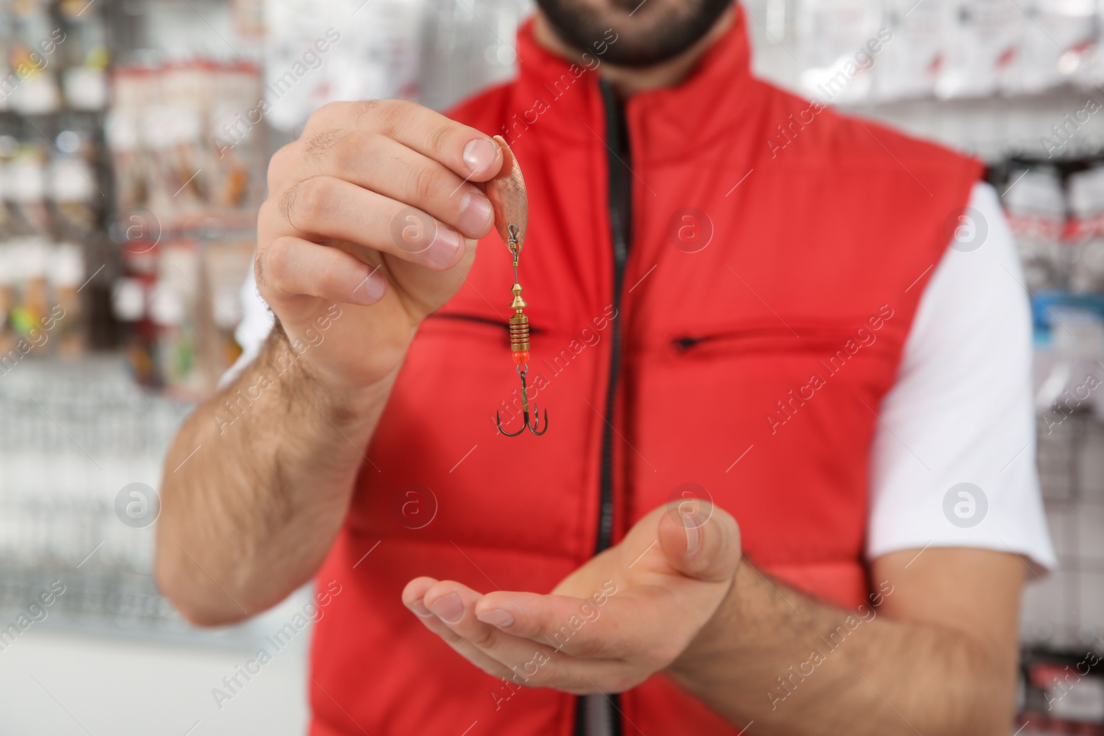 Photo of Salesman with fishing hook in sports shop, closeup