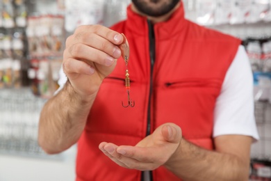 Salesman with fishing hook in sports shop, closeup