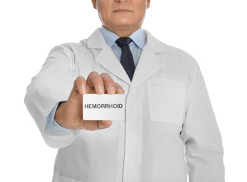 Doctor holding business card with word HEMORRHOID on white background, closeup