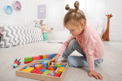 Photo of Cute little girl playing with colorful building blocks at home, space for text