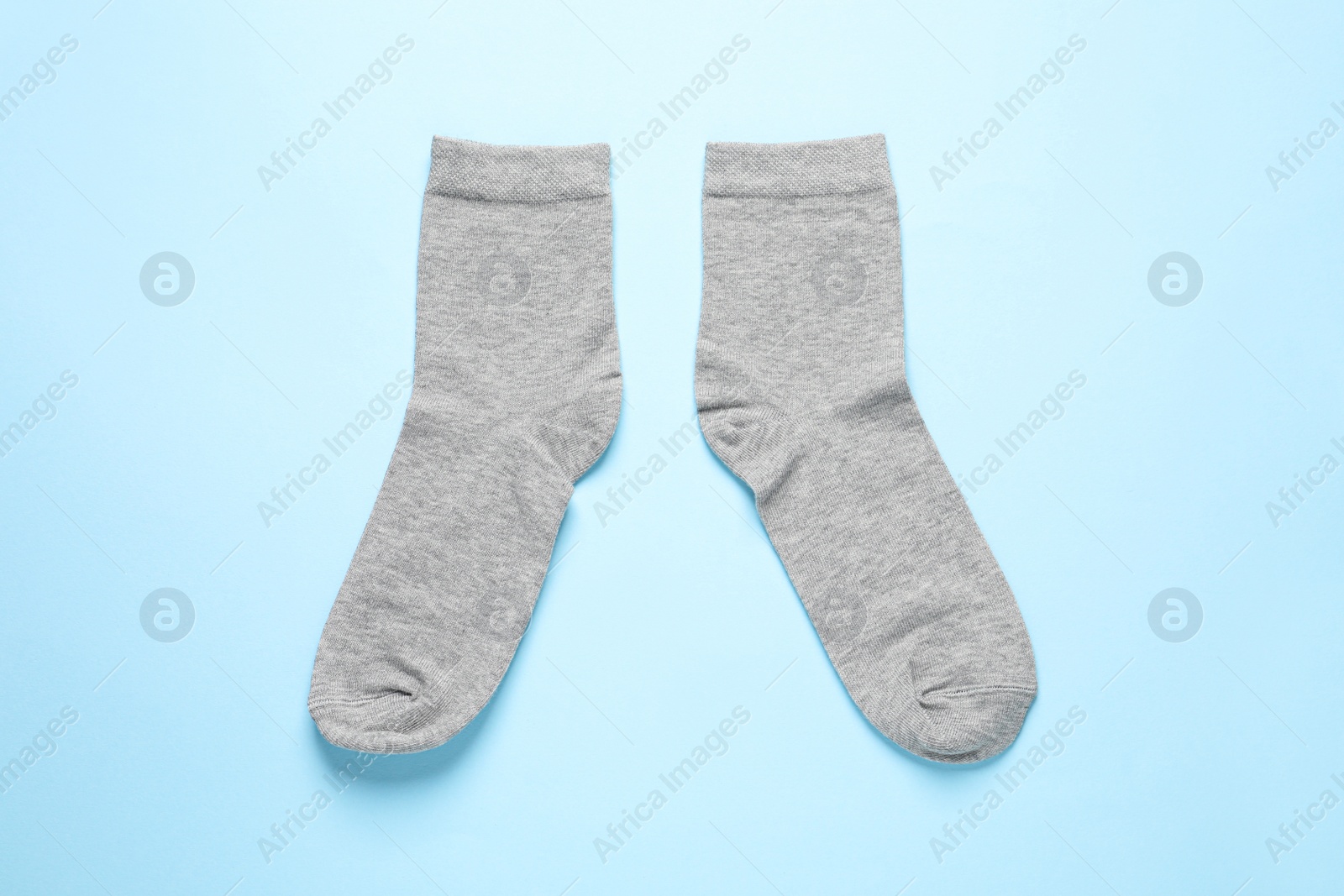 Photo of Pair of grey socks on light blue background, flat lay