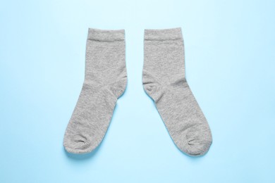 Pair of grey socks on light blue background, flat lay