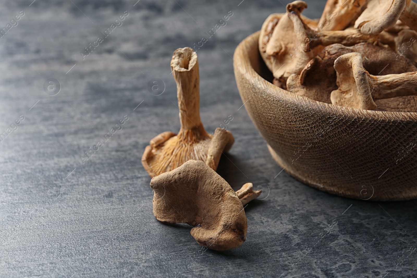 Photo of Bowl of dried mushrooms on color background, closeup