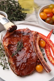 Raw marinated meat with thyme, chili pepper and basting brush on light table, closeup