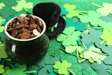 Photo of Pot of gold coins and hat on clover leaves, space for text. St. Patrick's Day celebration