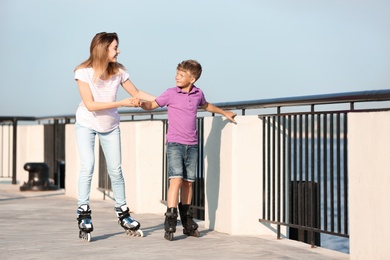 Mother and son roller skating on city street