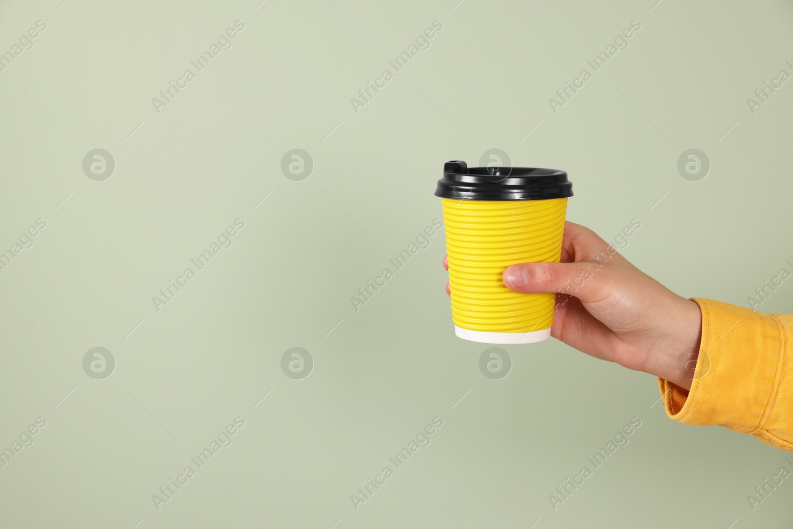 Photo of Woman holding takeaway cup with drink on pale green background, closeup view and space for text. Coffee to go