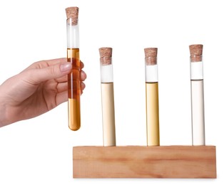 Woman taking test tube with light brown liquid from stand on white background, closeup