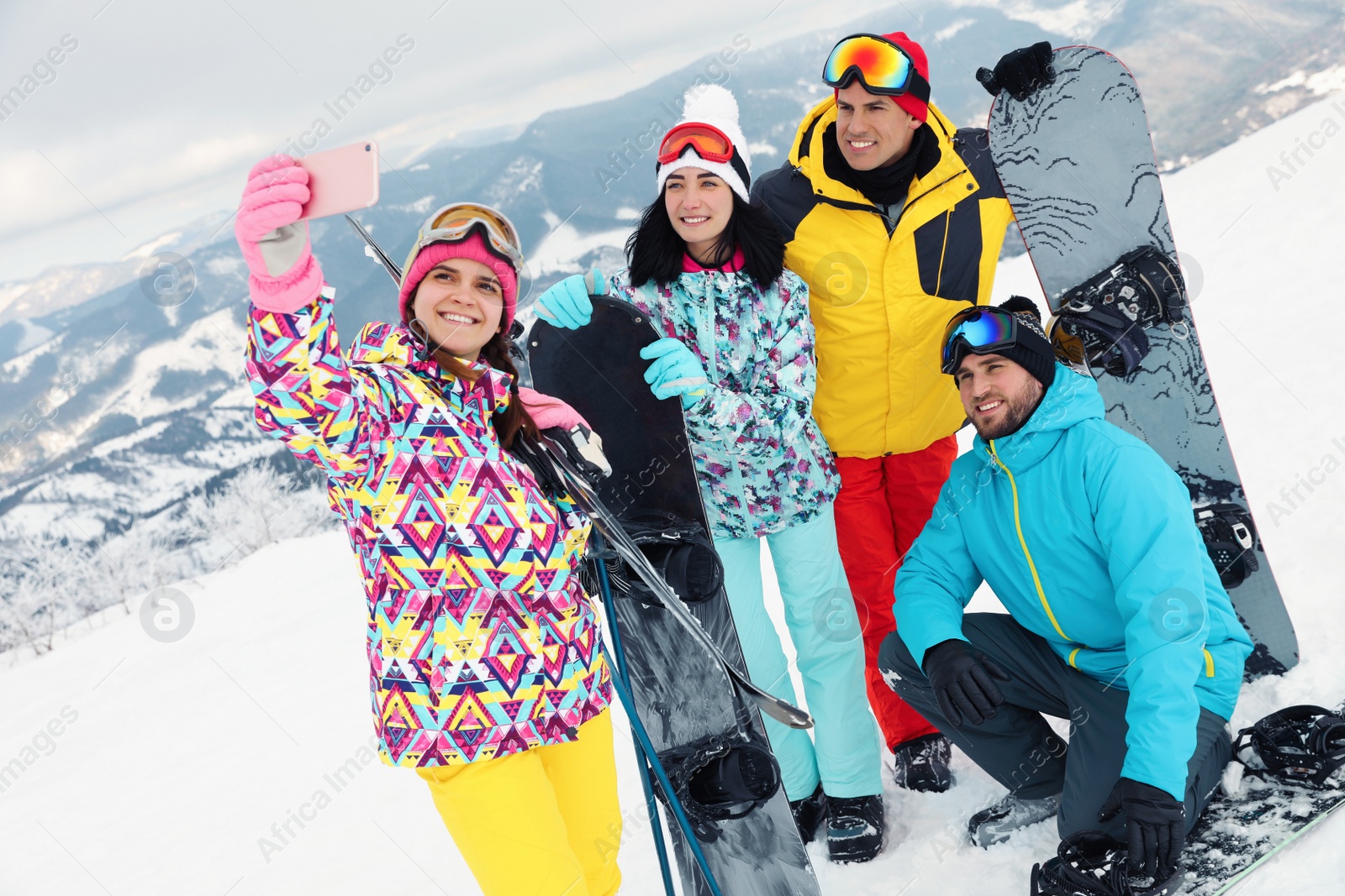 Photo of Group of friends taking selfie in snowy mountains. Winter vacation