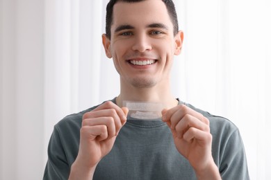 Photo of Young man with whitening strips on light background