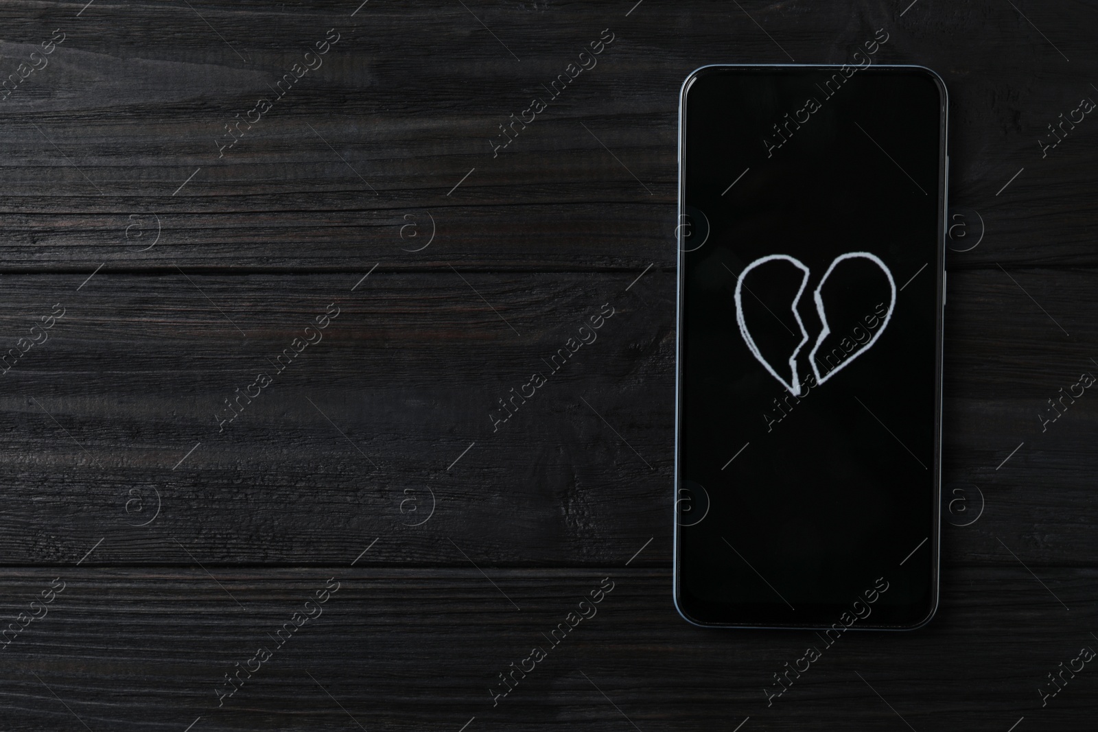 Photo of Smartphone with picture of broken heart and space for text on black wooden background, top view. Relationship problems concept