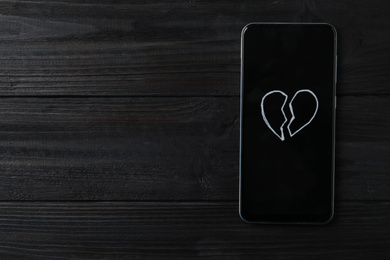 Photo of Smartphone with picture of broken heart and space for text on black wooden background, top view. Relationship problems concept