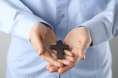 Woman holding wooden Christian cross, closeup view