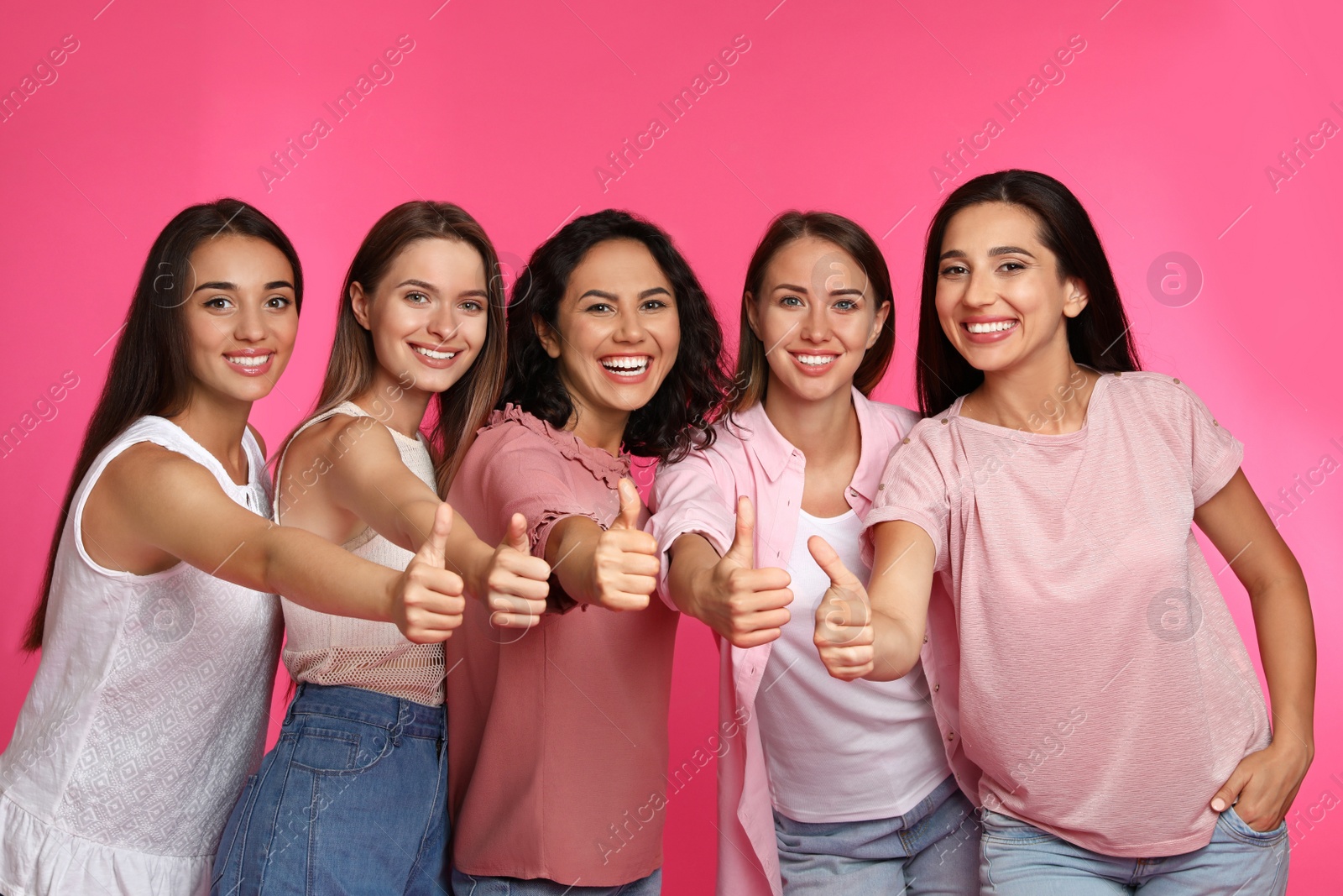 Photo of Happy women showing thumbs up on pink background. Girl power concept