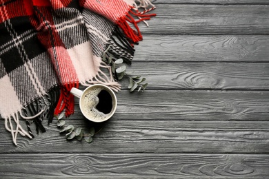 Photo of Flat lay composition with hot drink and warm plaid on black wooden table, space for text