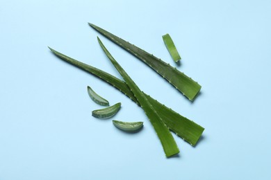 Photo of Cut aloe vera leaves on light blue background, flat lay