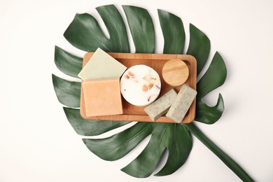 Photo of Wooden tray with eco friendly personal care products and green leaf on white background, top view