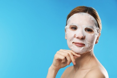 Photo of Beautiful woman with cotton mask sheet on face against color background. Space for text