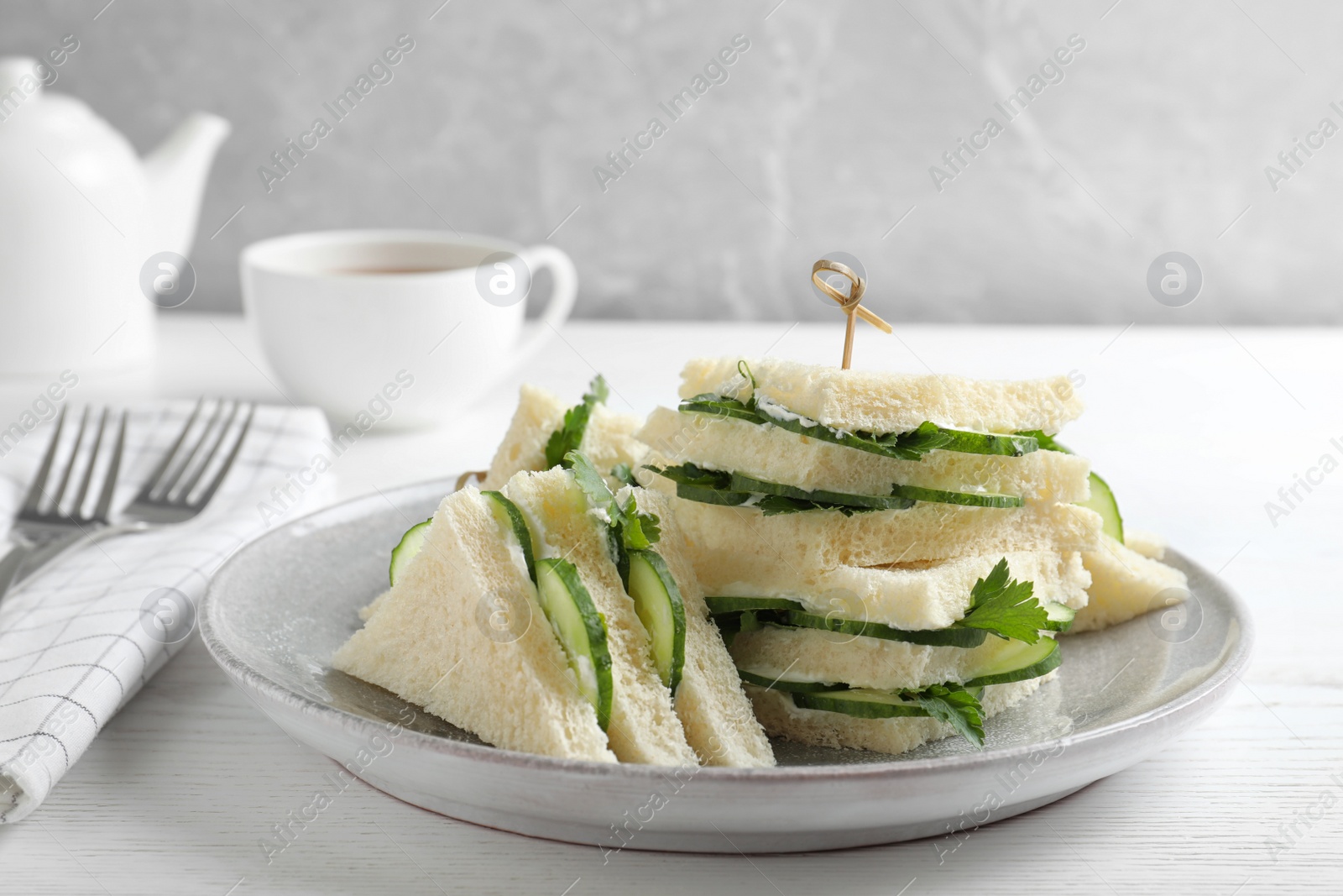 Photo of Plate with traditional English cucumber sandwiches on table