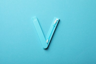 Photo of Reusable ear swab on light blue background, top view. Conscious consumption