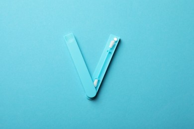 Reusable ear swab on light blue background, top view. Conscious consumption