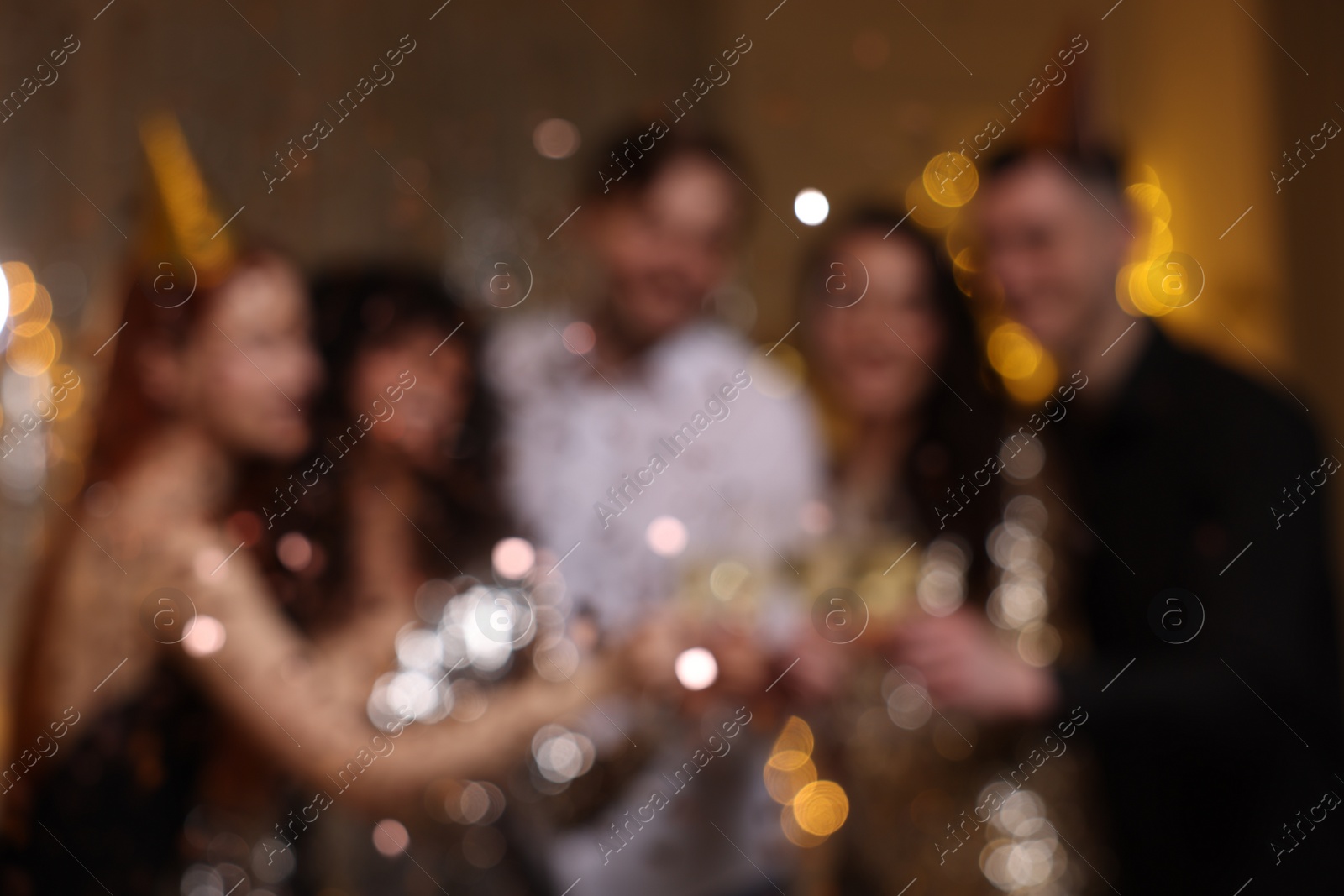 Photo of Blurred view of happy friends clinking glasses of sparkling wine at birthday party indoors