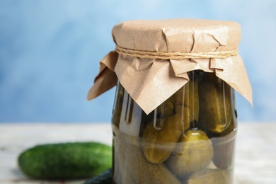 Photo of Jar with pickled cucumbers against blue background, closeup view