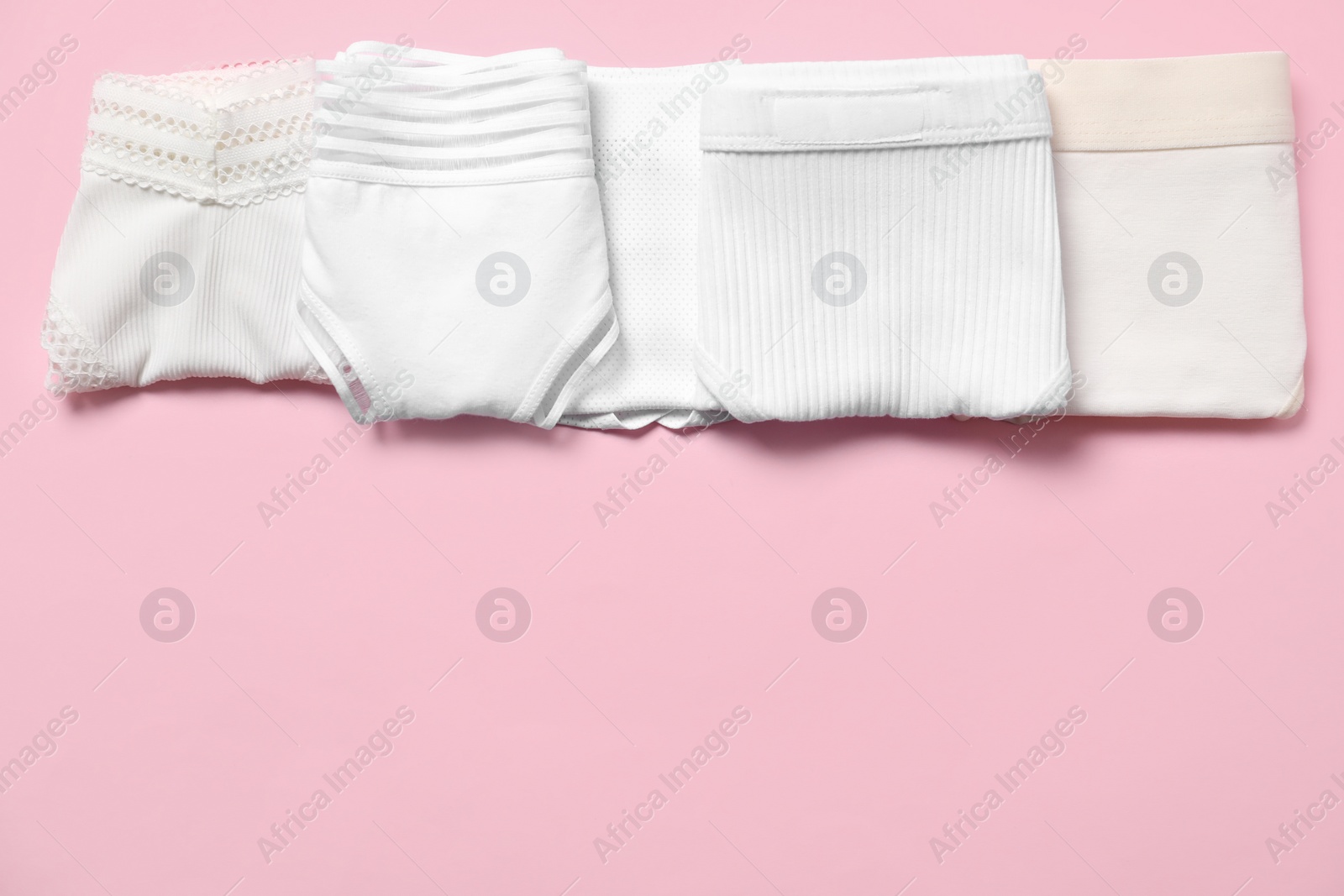 Photo of Stylish folded women's underwear on pink background, flat lay. Space for text