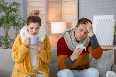 Photo of Couple suffering from cold together on sofa at home