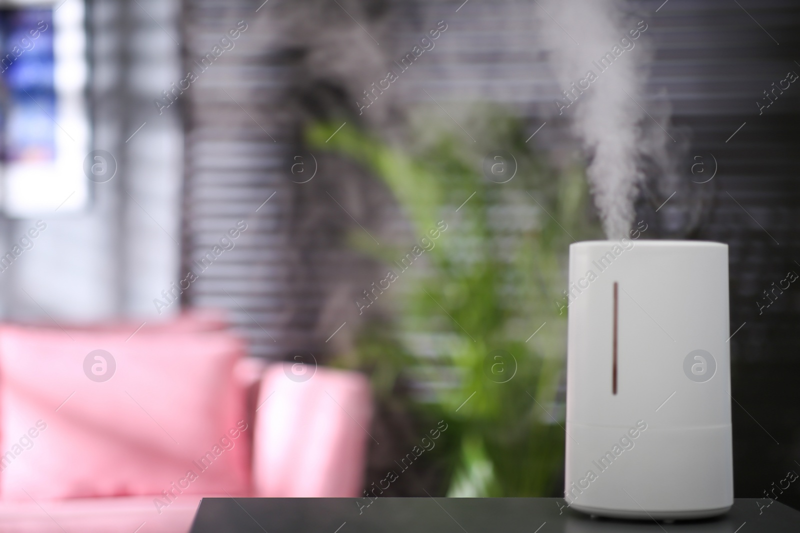 Photo of Modern air humidifier on table indoors. Space for text