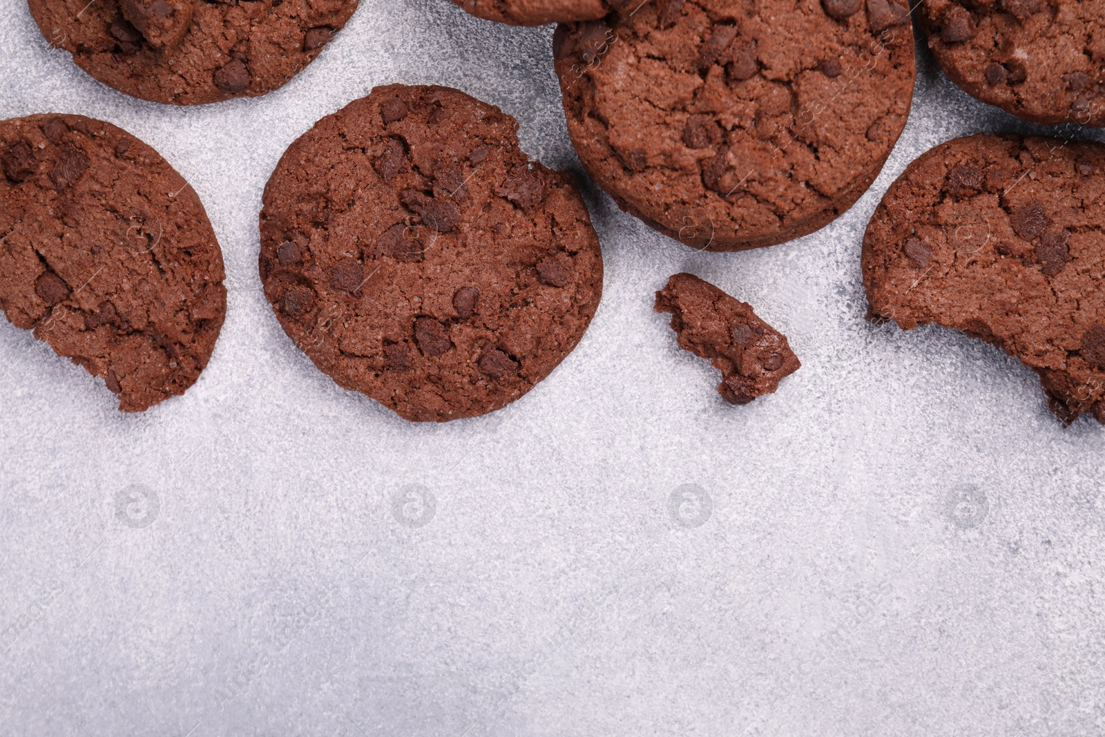 Photo of Tasty chocolate cookies on light grey textured table, flat lay. Space for text