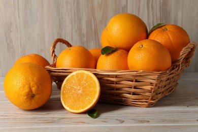 Many whole and cut oranges on light wooden table