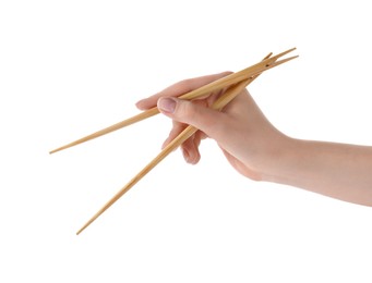 Woman holding pair of wooden chopsticks on white background, closeup