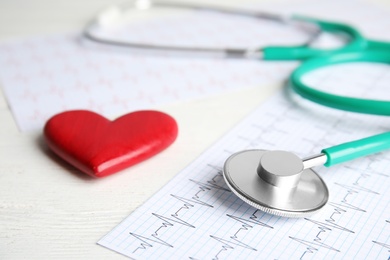 Stethoscope, red heart and cardiogram on wooden table. Cardiology concept