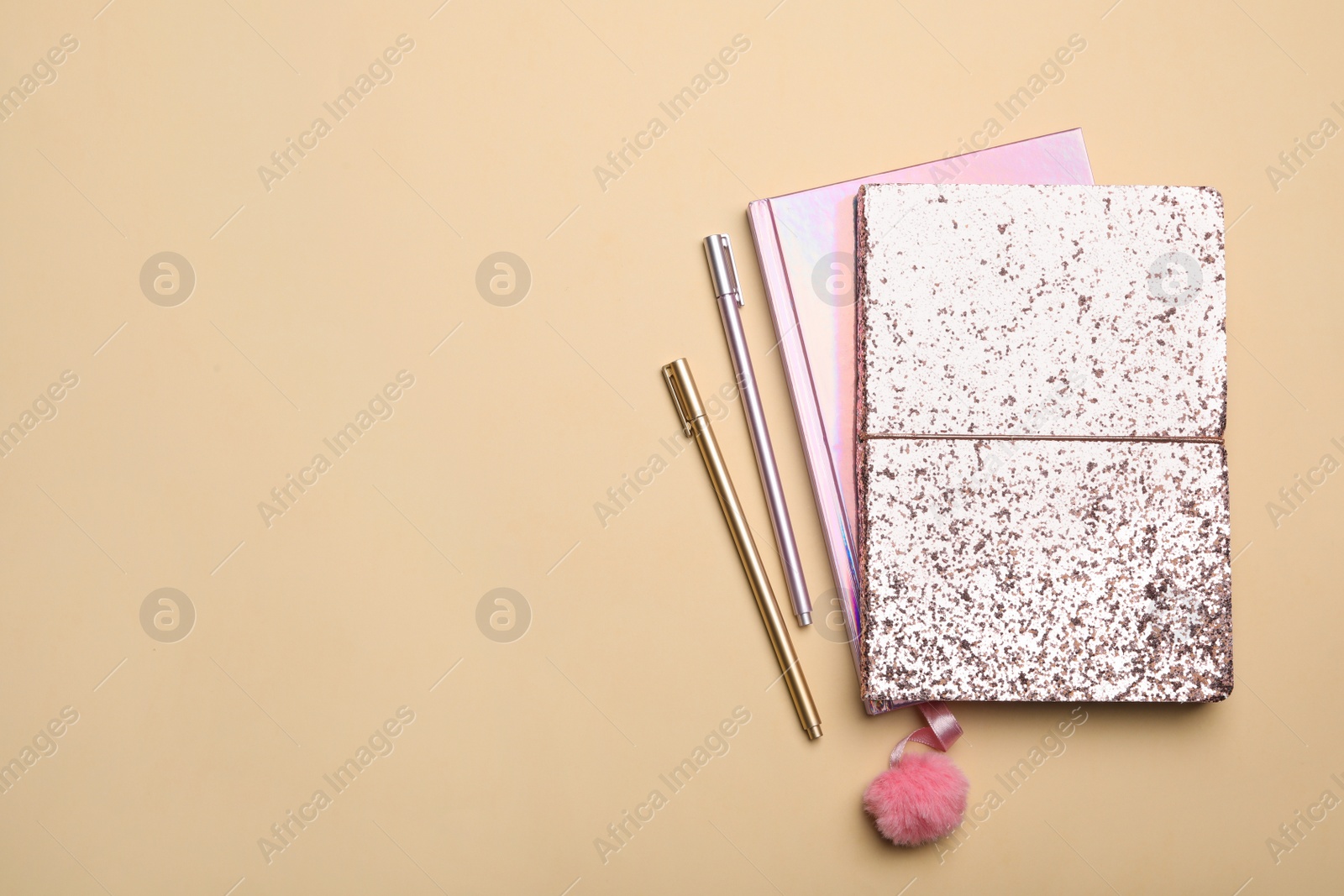 Photo of Pink notebooks and pens on beige background, flat lay. Space for text