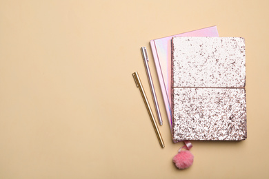 Photo of Pink notebooks and pens on beige background, flat lay. Space for text